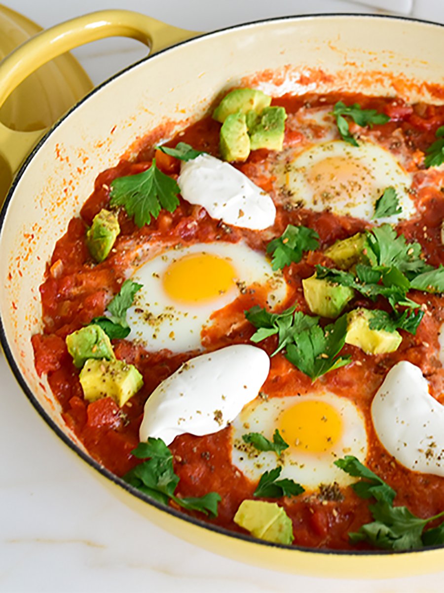 eggs poached in tomato in a yellow dish for shakshuka