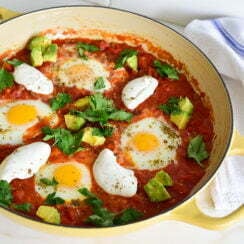 Shakshuka with avocado, labneh and za'atar in a round yellow baking dish