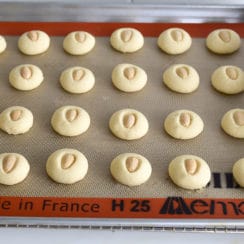 Almond graybeh on a sheet pan with a Silpat underneath the cookies