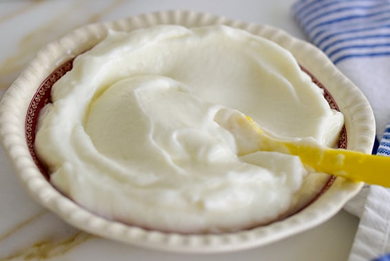 Lebanese toum garlic sauce, white fluff in a red and white dish with yellow spatula