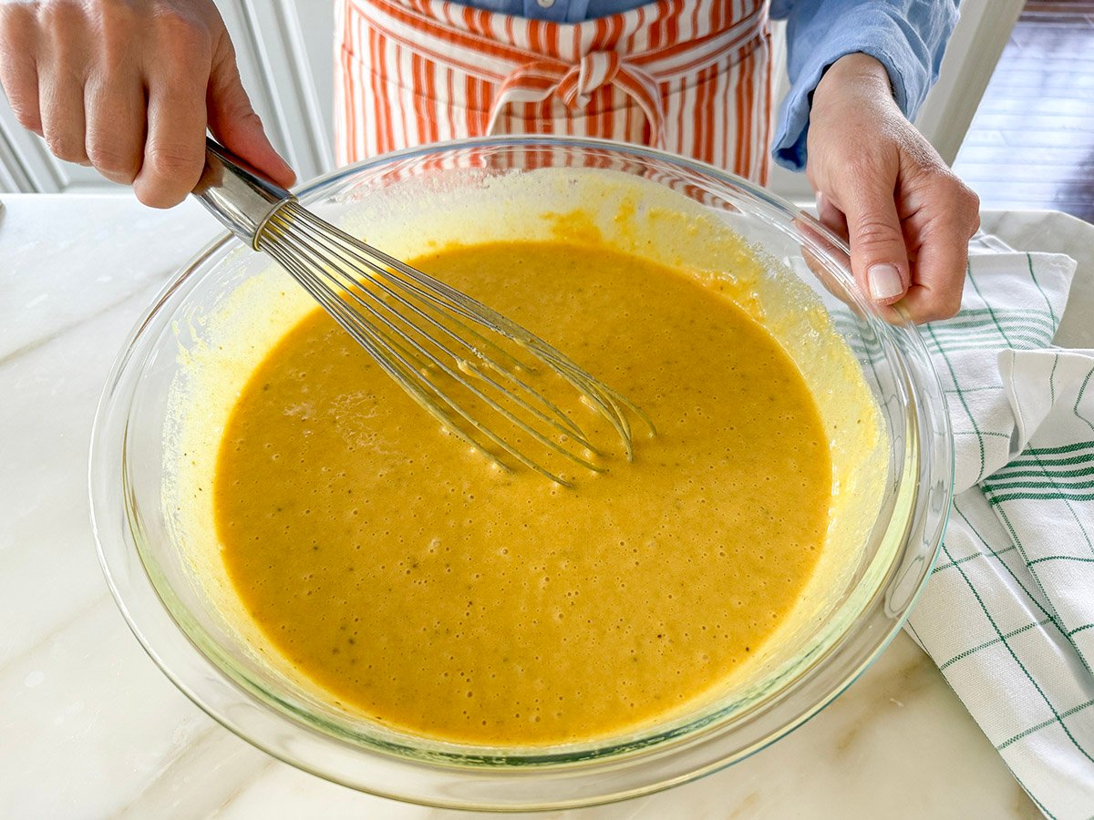 A whisk in a glass bowl of batter