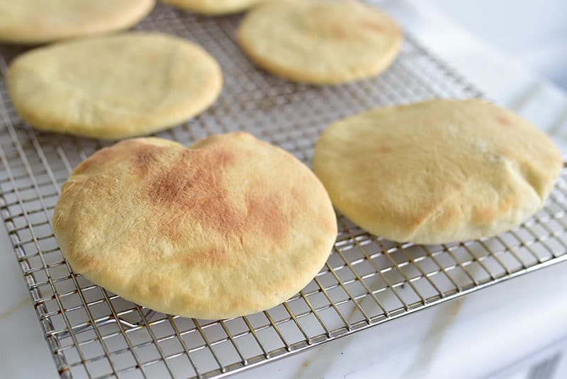 Homemade pita bread on a wire rack.