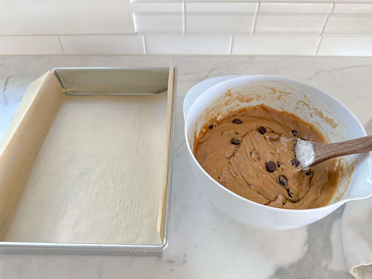 chocolate chip dough batter next to a parchment lined baking pan