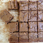 Blondie bars cut in squares on a sheet of parchment paper