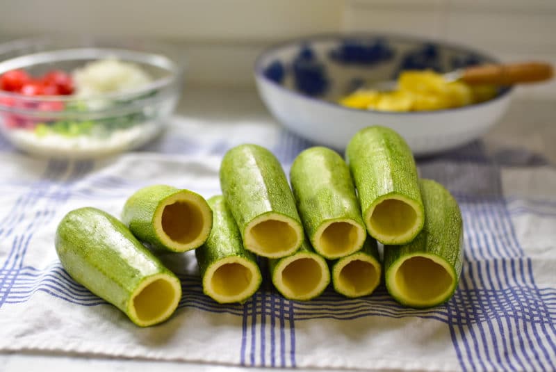 Light green kousa squash hollowed out in the middle, stacked on a towel on the counter