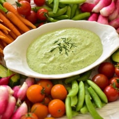 Labneh Green Goddess in an oval dish with crudite vegetables around it