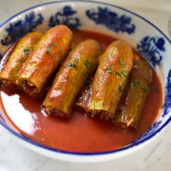 Green squash stuffed with rice with tomato broth in a blue and white bowl