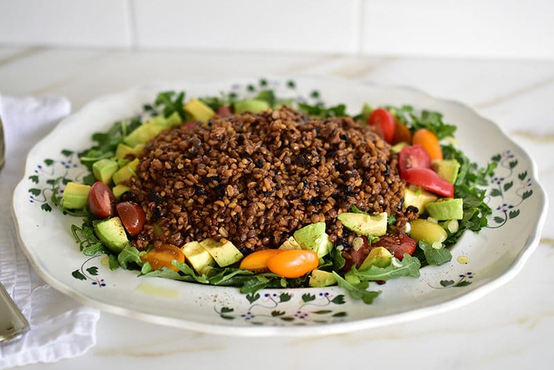 Arugula salad with mujadara on top on a big platter