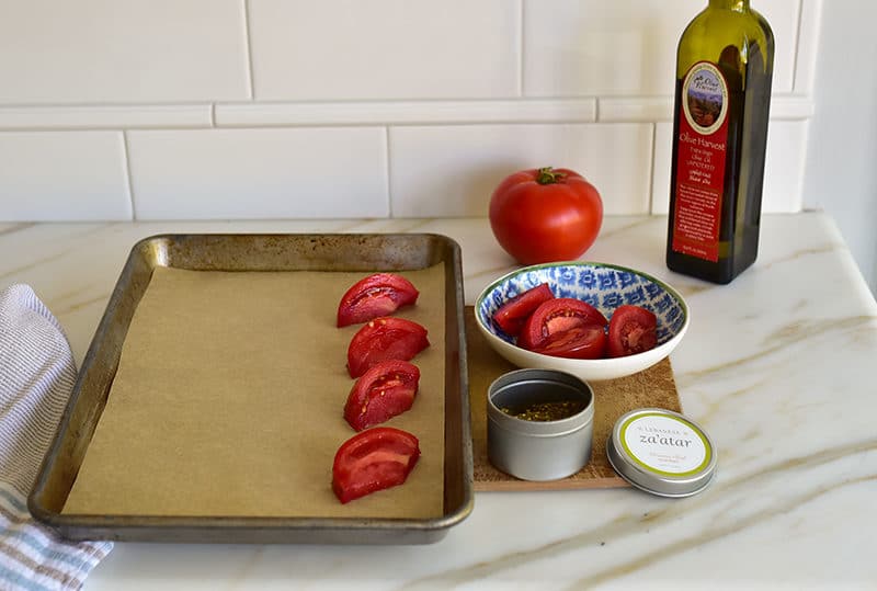 A tin of za'atar with sliced tomatoes and olive oil, prepped for roasting