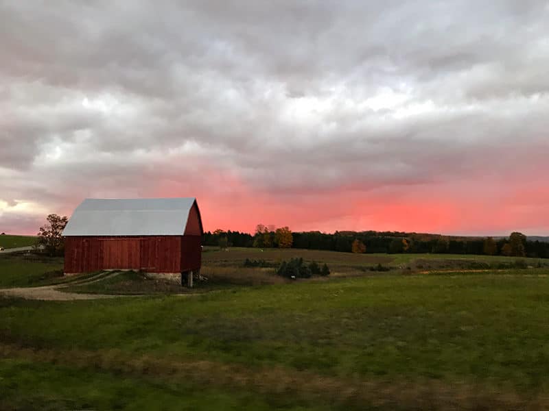 Pink sky and red barn over farmland up north in Michigan