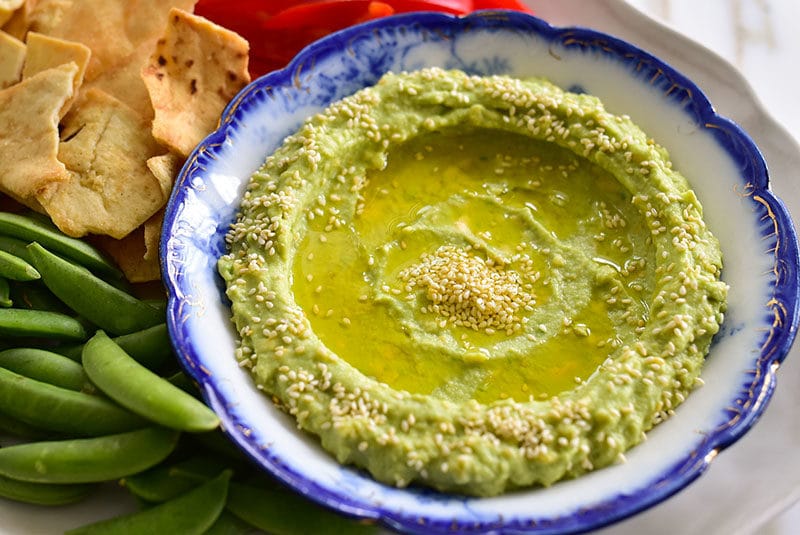 Avocado tahini dip with toasted sesame seeds and olive oil, spread in a blue dish