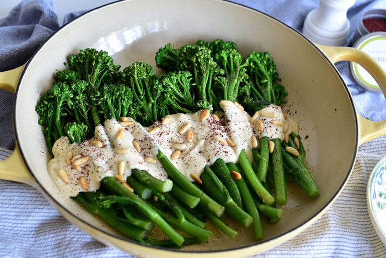Green Broccolini with Pine Nut Sauce and Sumac in a white enameled dish