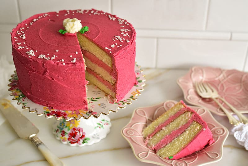 Raspberry buttercream cake slice on a pink plate.