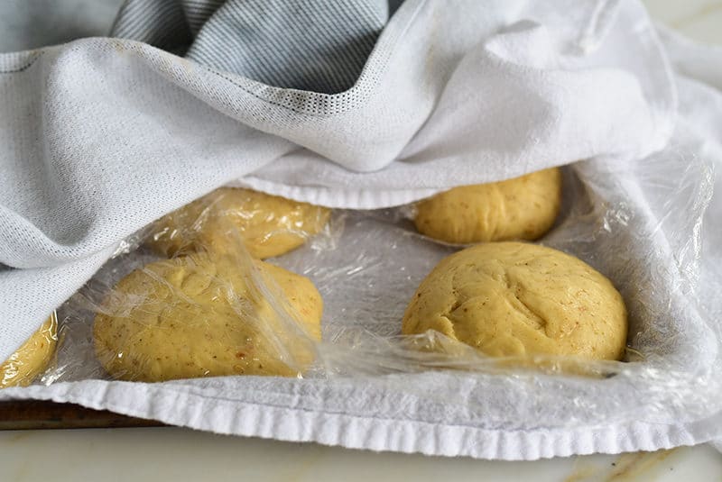 Risen dough balls on a sheet pan with towels