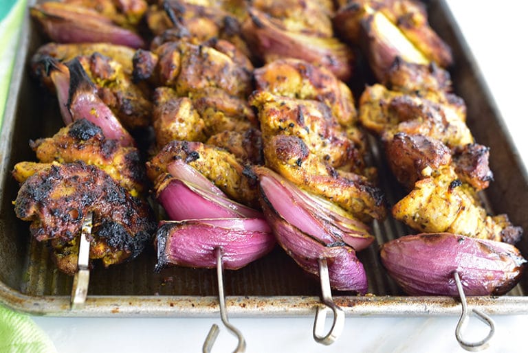 Grilled Chicken Shawarma Skewers with red onion on a sheet pan
