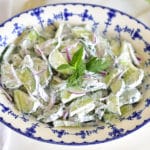 creamy cucumber salad with mint in a blue and white dish