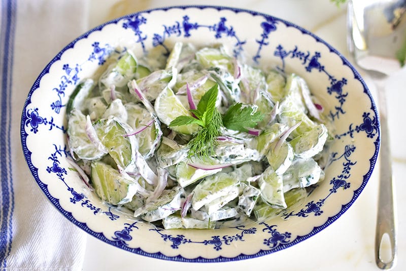 Cucumber salad with herbs in a blue bowl with a spoon