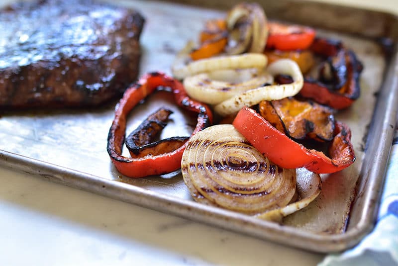 Grilled peppers and onions on a sheet pan with flank steak