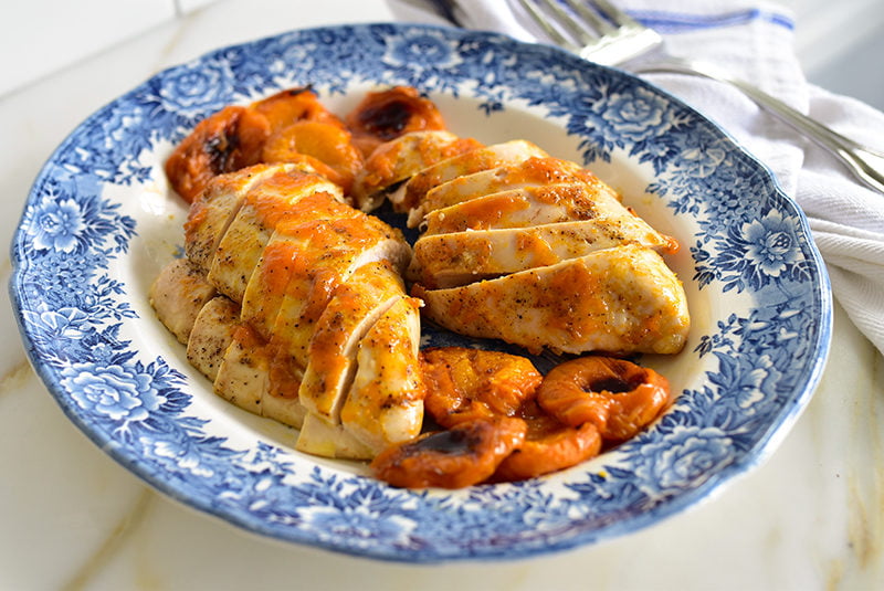 Apricot Chicken sliced with apricots on a blue platter