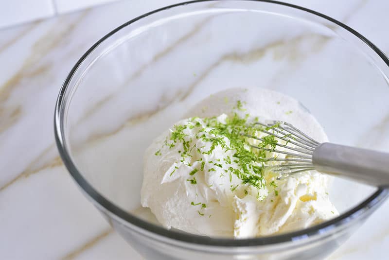 Labneh with cream cheese, sugar, and lime in a bowl with a whisk