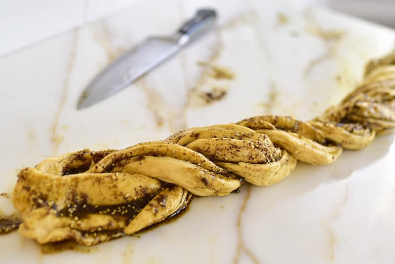 Dough filled with za'atar and olive oil and twisted next to a knife