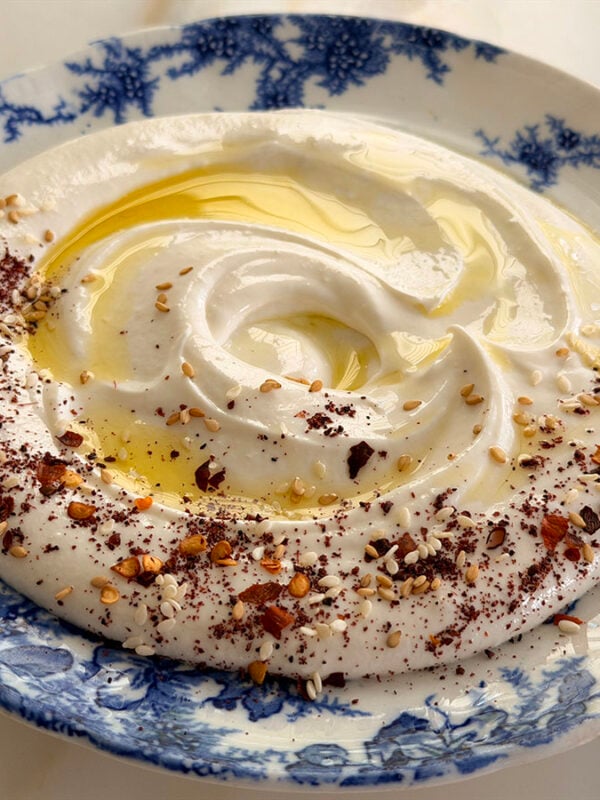 Whipped feta dip with olive oil on top on a blue and white plate