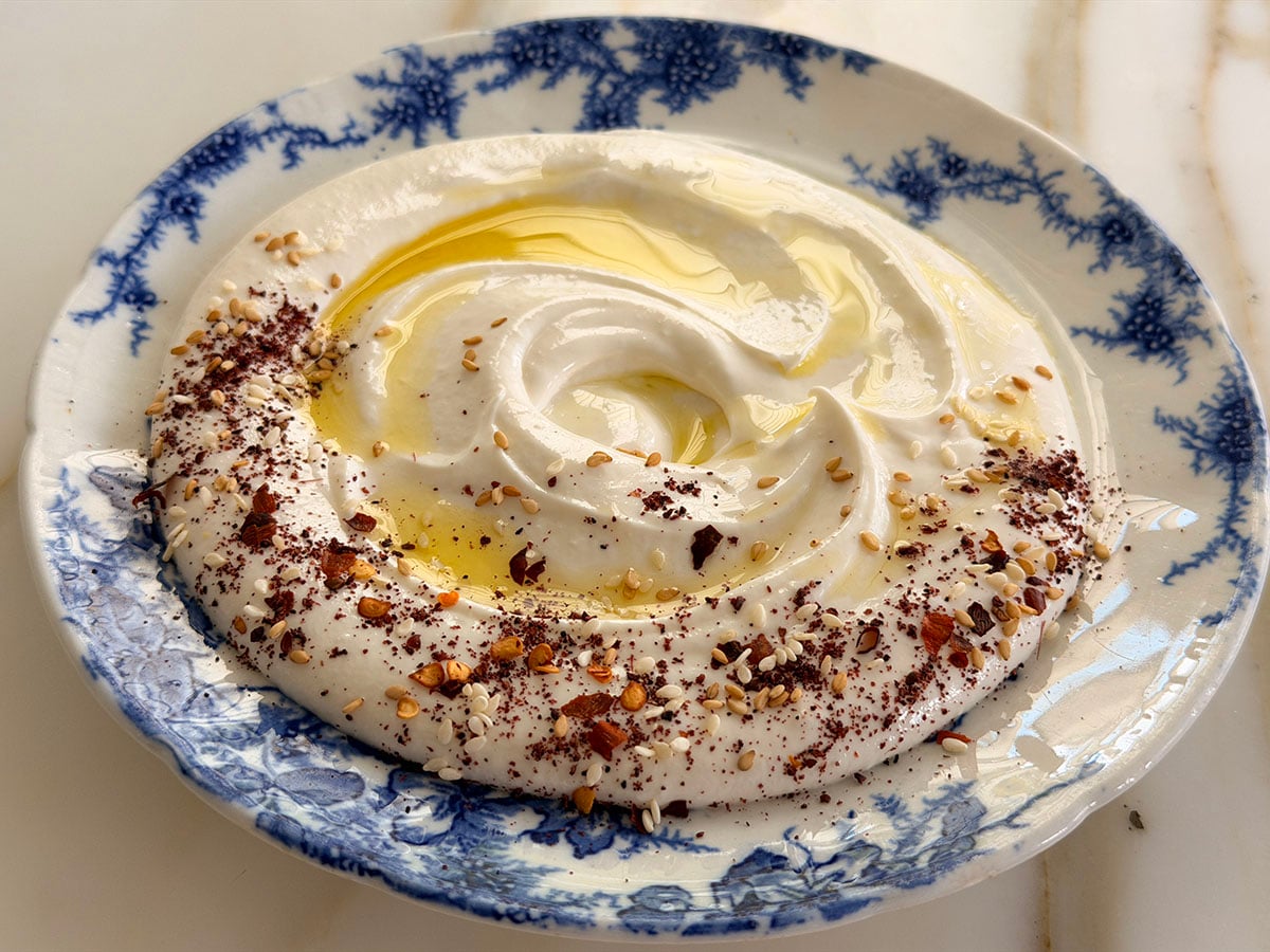 Whipped feta dip with olive oil on top on a blue and white plate