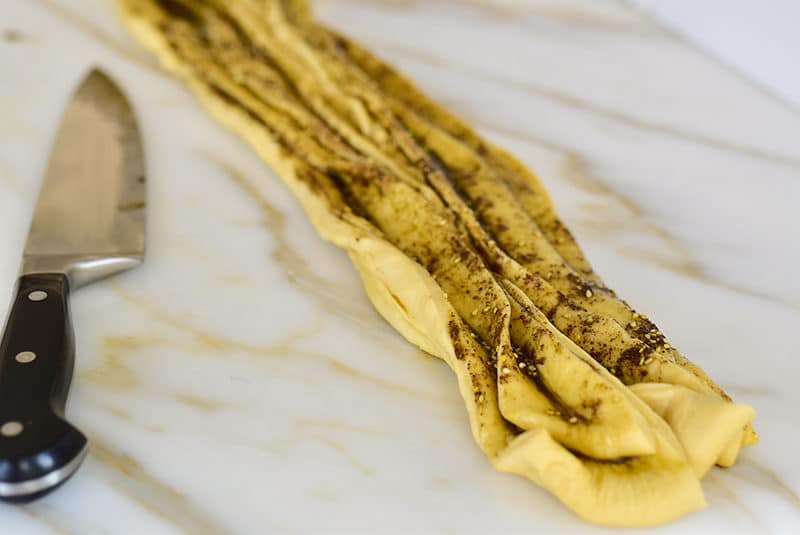 Layers of dough filled with za'atar and olive oil next to a knife