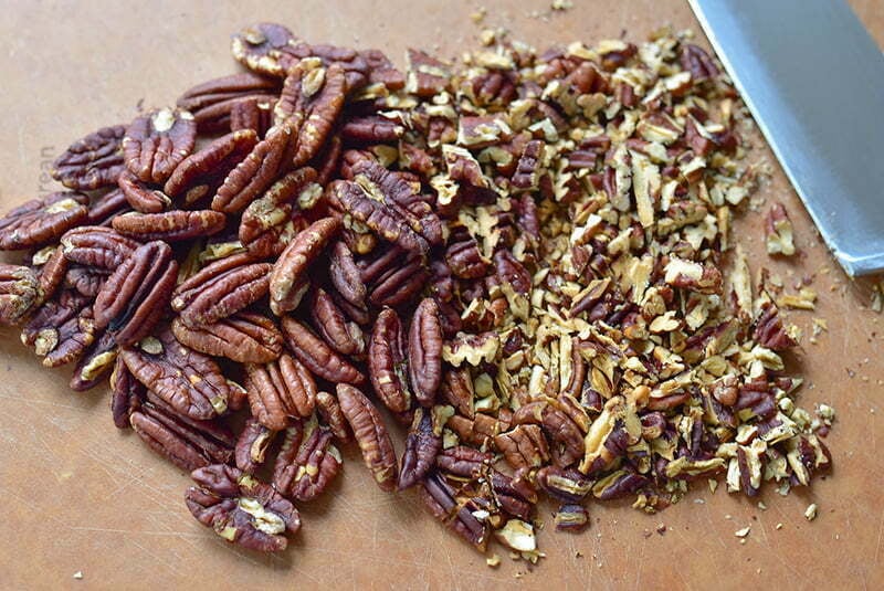 Chopped toasted pecans on a cutting board