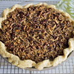 Pecan pie on a rack with green and white pot holders