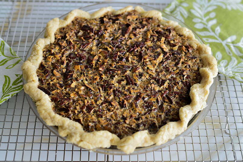 Pecan pie on a rack with green and white pot holders