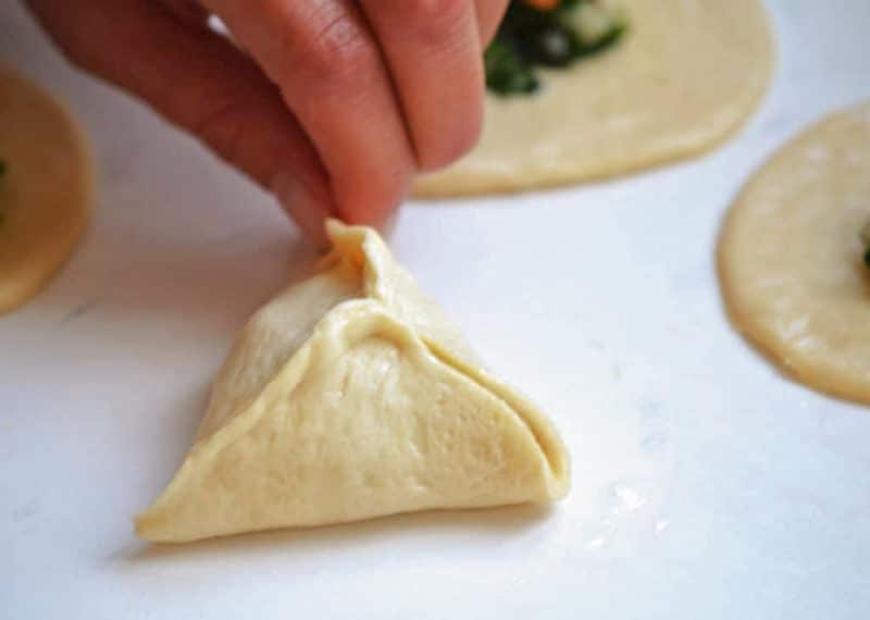 Fingers pinching fatayer dough seams