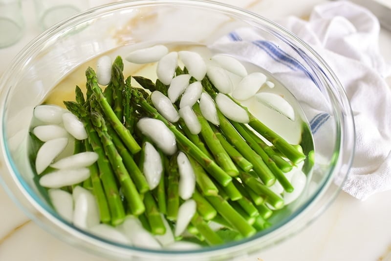 Blanched asparagus in bowl of ice