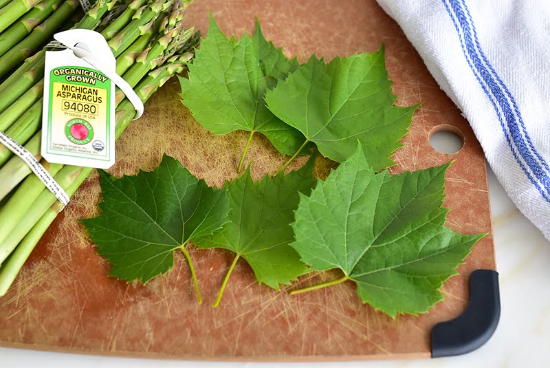 Asparagus with grapeleaves on a cutting board
