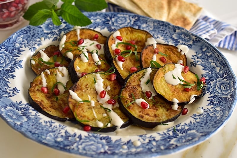 Lebanese eggplant on a blue platter with tahini sauce