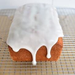 Olive oil loaf cake with white glaze on a rack