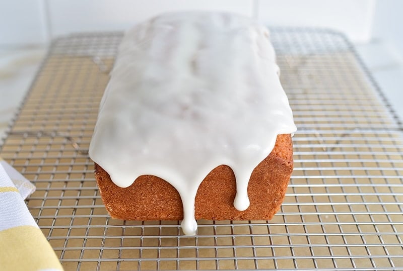 Olive oil loaf cake with white glaze on a rack