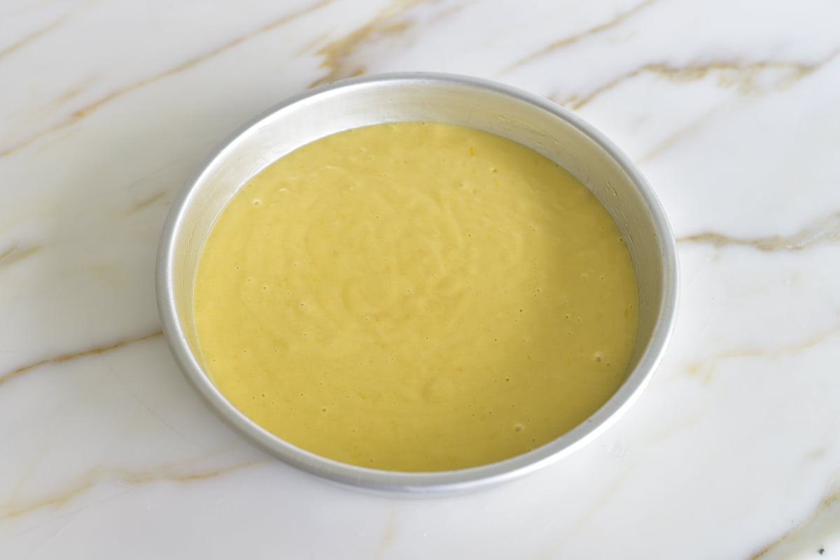 Yellow cake batter in a silver round cake pan