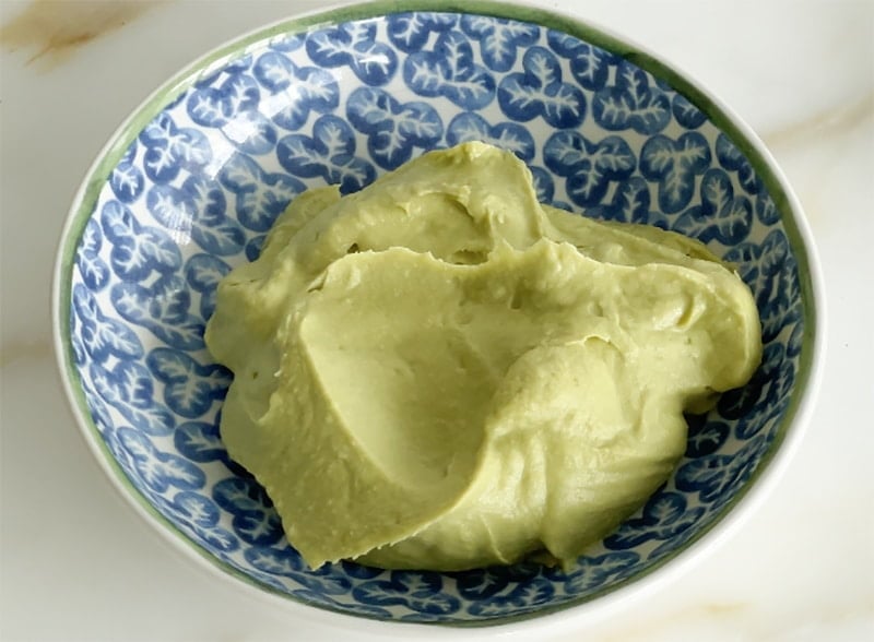 Dollop of avocado hummus in a blue bowl