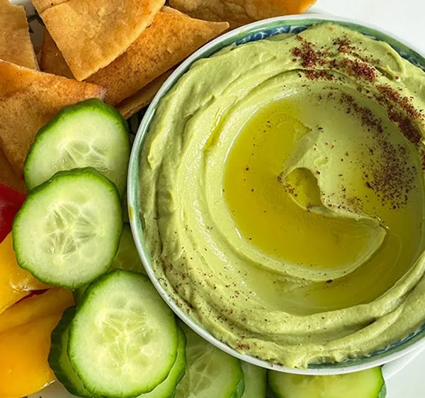 Avocado hummus with olive oil and sumac in a round dish