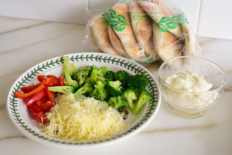 Plate with broccoli, peppers, and cheese with pita in a bag