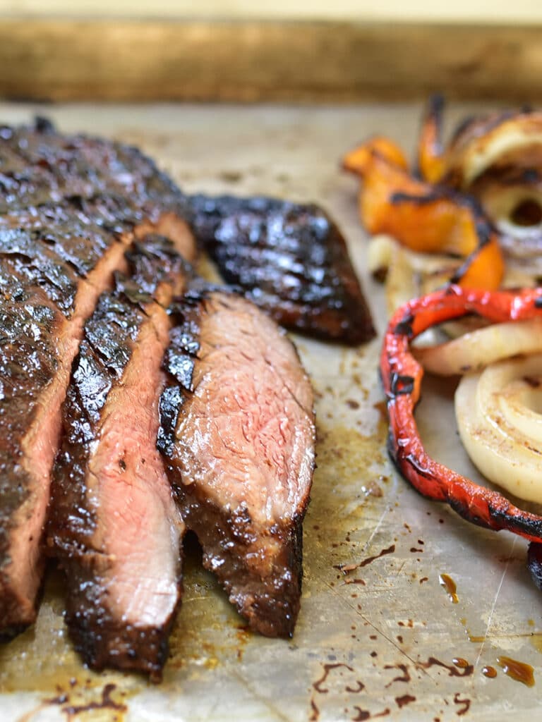 Sliced pomegranate marinated flank steak with peppers