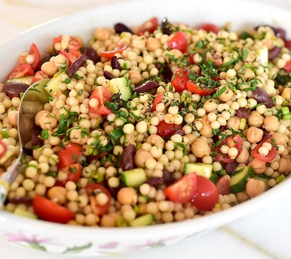 Lebanese couscous salad with a spoon in a white dish