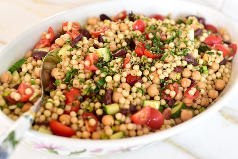 Lebanese couscous salad with a spoon in a white dish