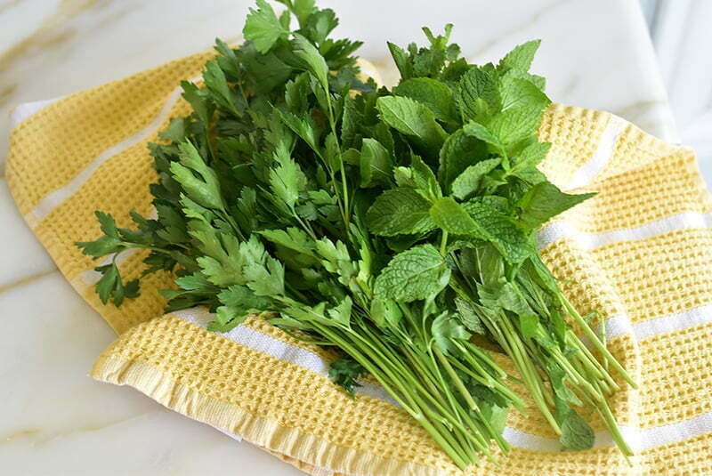 Fresh herbs in a yellow kitchen towel on the counter