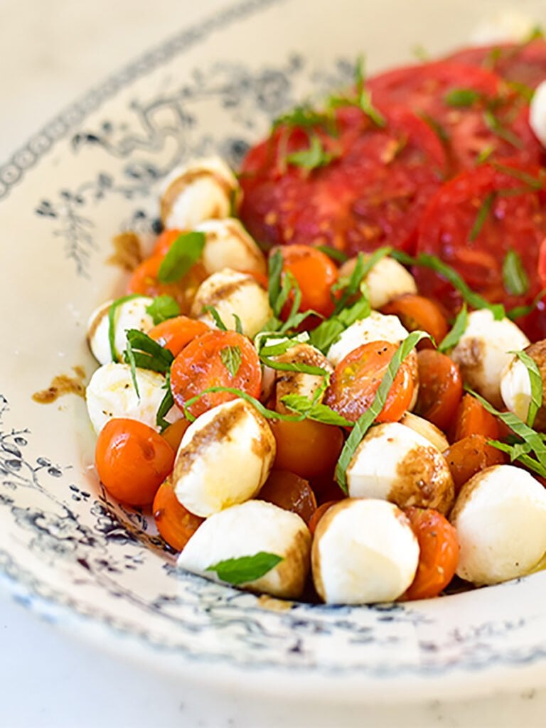 Tomato mozzarella salad caprese with pomegranate on a blue and white platter