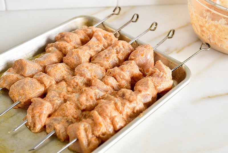 Skewered chicken for shish Tawook on a pan.