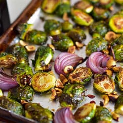 Halved brussels sprouts and sliced red onion on a sheet pan