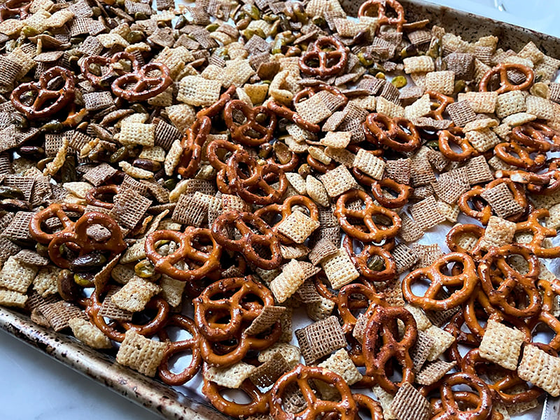 Chex mix on a sheet pan before baking with olive oil