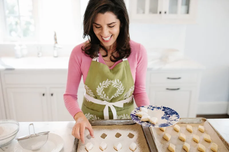 Maureen Abood picking up ghraybeh cookies and placing them on a blue and white plate